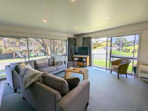 uma sala de estar com dois sofás e uma televisão em The Coastal Getaway em Mount Maunganui