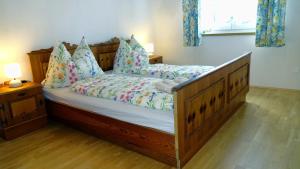 een slaapkamer met een groot houten bed met kussens bij Ferienwohnung Margit in Förolach