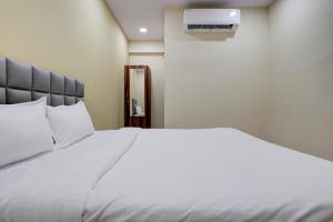 a bedroom with a white bed and a air conditioner at OYO Hotel 7 Star in Surat
