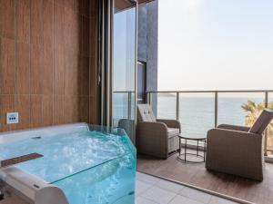 a hot tub in a room with a view of the ocean at Alba HOTEL & Glamping in Nishinoura