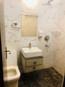 W łazience znajduje się toaleta, umywalka i lustro. w obiekcie The highland hotel w mieście Bathinda
