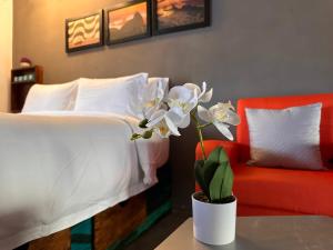 1 dormitorio con 1 cama y un jarrón con flores sobre una mesa en Brazilian Art & Free Parking - emitimos factura en Quetzaltenango