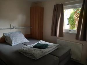 a bedroom with a bed with a blanket and a window at Lodge Damian op de Veluwe in Voorthuizen +25 photos