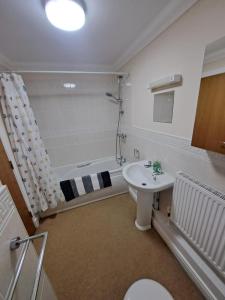 a bathroom with a tub and a toilet and a sink at The Elms Apartments Ramsey Isle of Man UK in Ramsey