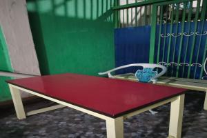una mesa roja y una silla blanca frente a un edificio en SPOT ON 93375 Elang Homestay, en Parit