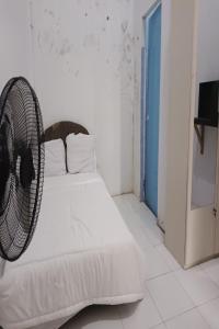 a bedroom with a white bed with a fan at SPOT ON 93375 Elang Homestay in Parit