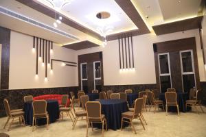 a conference room with tables and chairs and chandeliers at Kings Bury Inn in Kumbakonam