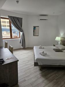 Habitación blanca con cama y ventana en Napoli Suites, en San Julián