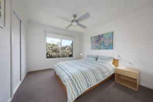 um quarto branco com uma cama e uma janela em Bayview Bliss em Surf Beach