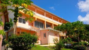 an orange and white building with trees in front of it at Bougainvillea Apartments in Saint Georgeʼs