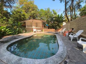 a swimming pool in a yard with chairs and a house at Greek "Jungle Villa", Thalassa Road, Standing alone 3bhk villa with pool in Siolim