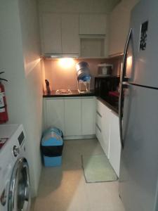 a small kitchen with a refrigerator and a trash can at Condo de Avila in Boracay
