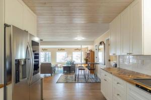 uma cozinha com armários brancos e um frigorífico de aço inoxidável em Lakefront Serenity 