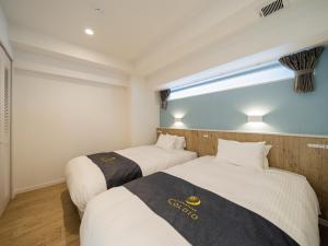 two beds in a room with a window at Aqua Palace Chatan by Coldio Premium in Chatan