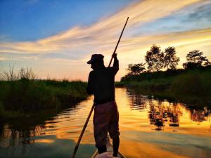 Un uomo sta remando su un fiume con un palo di Barahi Jungle Lodge a Meghauli