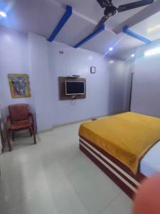 um quarto com uma cama, uma televisão e uma cadeira em HOTEL KANHA INTERNATIONAL, Anuppur em Anūppur