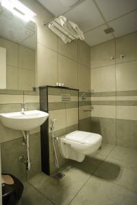 a bathroom with a sink and a toilet and a mirror at Sulu Residency in Ernakulam