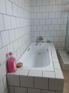 W łazience znajduje się wanna i różowa butelka mydła. w obiekcie Mpucuko Guest House w mieście Mtubatuba