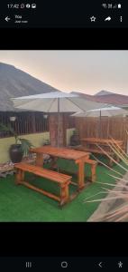 una mesa de picnic y bancos con sombrilla en Mpucuko Guest House en Mtubatuba