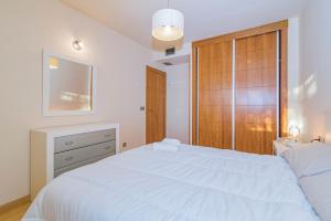 a bedroom with a white bed and a wooden door at Playa Granada Motril Beach and Golf in Motril +15 photos
