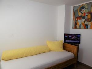 a bed with a yellow pillow and a tv at Apartment in Krimml with a balcony or terrace in Krimml