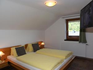 Apartment in Krimml with a balcony or terrace في كريمل: غرفة نوم بسرير مع شراشف صفراء ونافذة