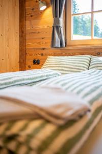 Cama en habitación de madera con ventana en Gloans Glück Ferienhaus en Frasdorf