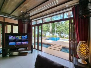a living room with a tv and a large window at Amatapura Beachfront Villa 15, SHA Certified in Ao Nam Mao