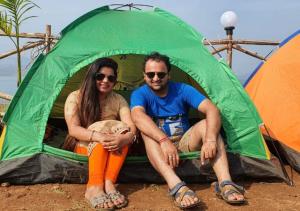 a man and a woman sitting in a tent at Pawna lake Camping Lonavala in Kolvan