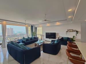 uma sala de estar com sofás azuis e uma televisão em Premium Apartment in Hiranandani Powai by Maxxvalue - Chitranjan em Mumbai