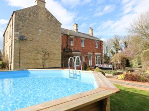 an outdoor swimming pool in front of a house at The Coach House in Grantham