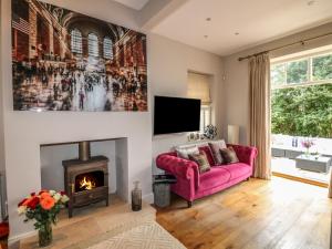 a living room with a pink couch and a fireplace at The Coach House in Grantham