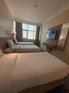 una camera d'albergo con due letti e una televisione di Nawazi Towers Hotel a La Mecca