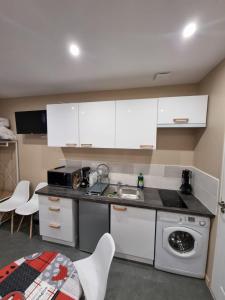 una cucina con armadi bianchi, lavandino e lavastoviglie di Studio Montry a Montry