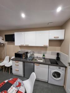 a kitchen with white cabinets and a sink and a dishwasher at Studio Montry in Montry +1 photo