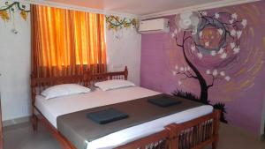 a bedroom with a bed with a tree painted on the wall at Samsara Harmony Beach Resort in Varkala