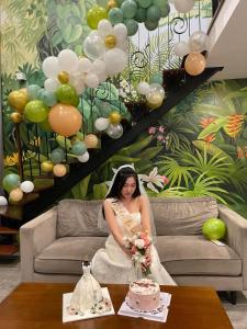 a woman in a wedding dress sitting on a couch with a cake at FlowerGod PentStudio Tay Ho Hanoi in Hanoi
