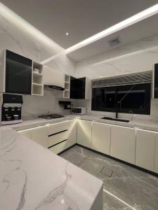 uma grande cozinha branca com armários e electrodomésticos brancos em شاليه الرتاج الفندقي em Buraydah