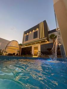 uma casa com piscina em frente a um edifício em شاليه الرتاج الفندقي em Buraydah
