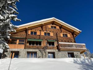 een groot houten huis met sneeuw ervoor bij Sunnehuesli in Braunwald