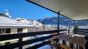 balcón con mesa y vistas a la montaña en La Golette Apartment, en La Thuile