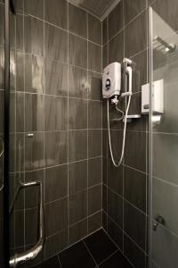 een badkamer met een douche en een haardroger aan de muur bij The Explorer Hotel in Melaka