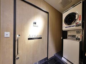 uma porta num quarto com uma máquina de lavar roupa em APA Hotel Kayabacho Hachobori Ekimae em Tóquio
