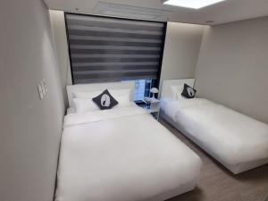 HOTEL THE DESIGNERS LYJ SUITE YEOKSAM في سول: سريرين في غرفة ذات أغطية ووسائد بيضاء