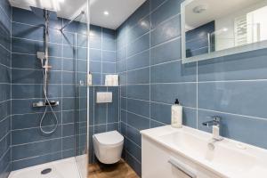 a blue tiled bathroom with a toilet and a shower at SmartStay Bird Family - Lyon in Lyon