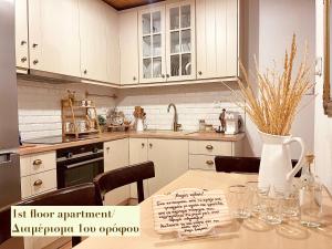 una cocina con armarios blancos y una mesa con jarrón en Casa Delicosta- 2 Flat Country house with garden, 15 min from Trikala, en Tríkala