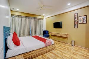 a bedroom with a bed and a flat screen tv at OYO Hotel Green Signature in Surat