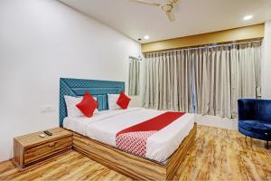 a bedroom with a bed and a blue chair at OYO Hotel Green Signature in Surat