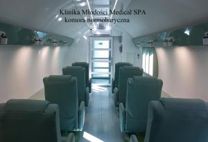 - une salle d'attente avec des chaises vertes dans un train dans l'établissement Klinika Młodości Medical SPA, à Świeradów-Zdrój