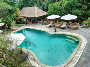 uma piscina com cadeiras e guarda-sóis ao lado de um resort em The Gana Ubud by Guru experience em Ubud